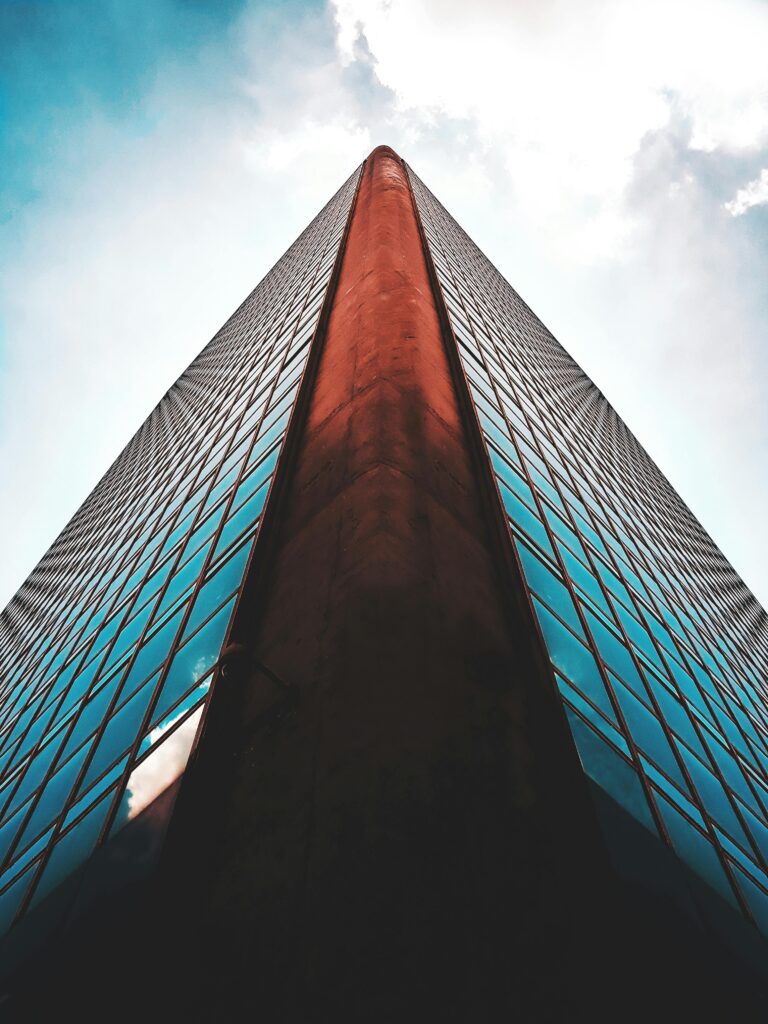 Striking low angle view of a modern skyscraper with reflective glass windows against a blue sky.