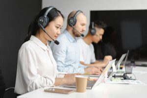 Customer service agents efficiently handle calls using laptops and headsets in a modern office.