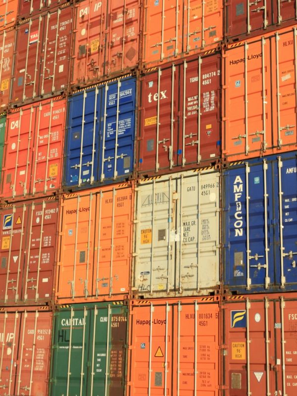 Colorful shipping containers stacked in a harbor, symbolizing global trade.