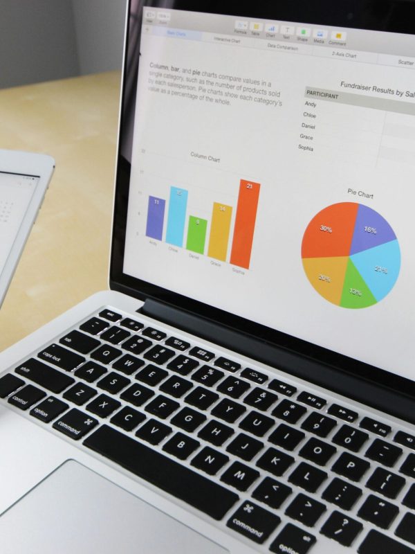 Laptop displaying charts and graphs with tablet calendar for data analysis and planning.