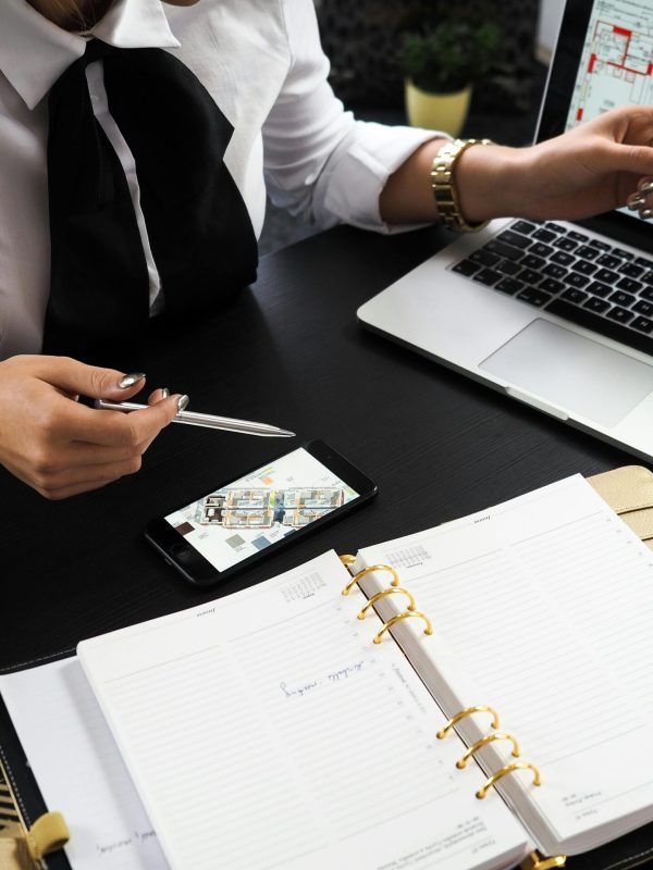 A business professional working on real estate project plans using multiple devices in an office setting.