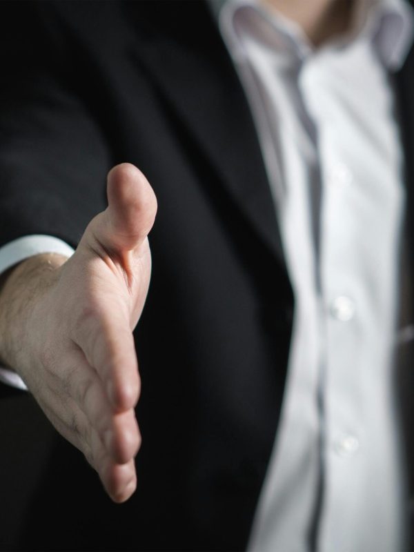 Close-up of a businessman extending hand for a handshake, symbolizing agreement and partnership.