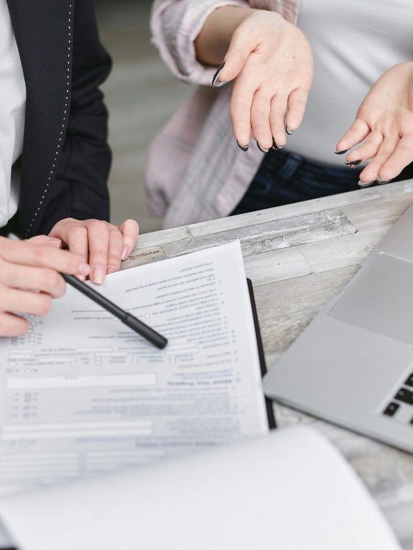 Two professionals discussing a contract at a business meeting with documents and a laptop.